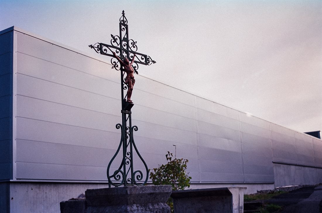 Haute-Loire, arrière d'un immense bâtiment commercial, croix avec statue de Jésus, teinte violette